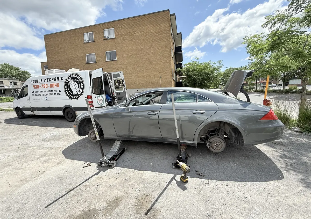 Grey Mercedes CLS on two floor jacks with front and rear wheels removed, next to the Alimotorsforall mobile mechanic van