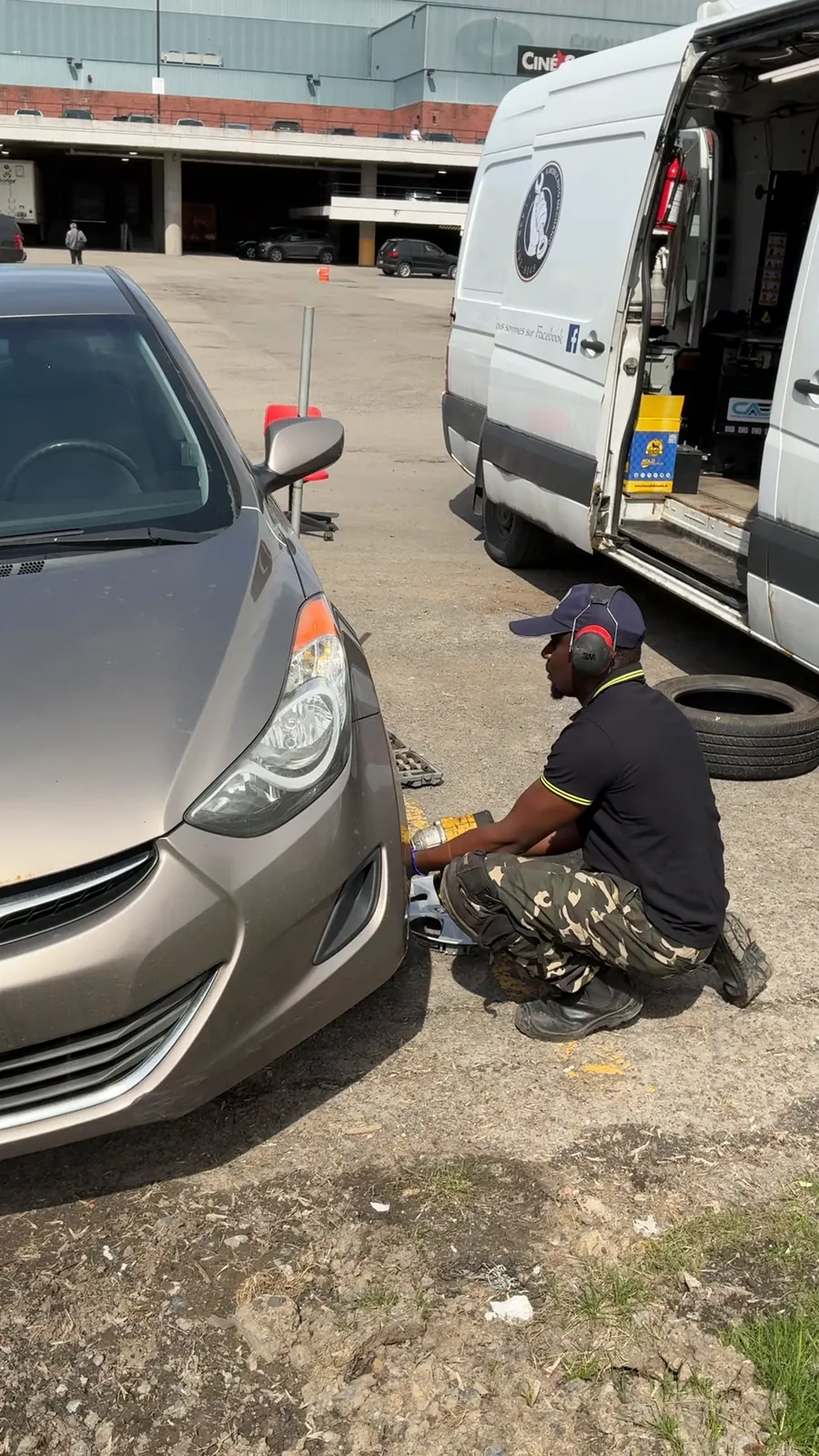 Mechanic removing a wheel with an impact wrench next to the van