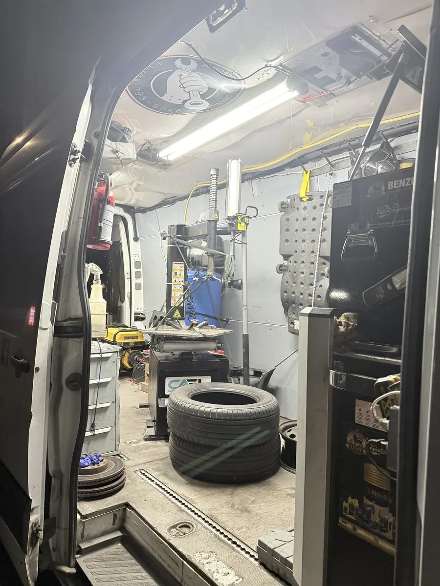 Inside the lit service van at night: tire changer, compressor and tools